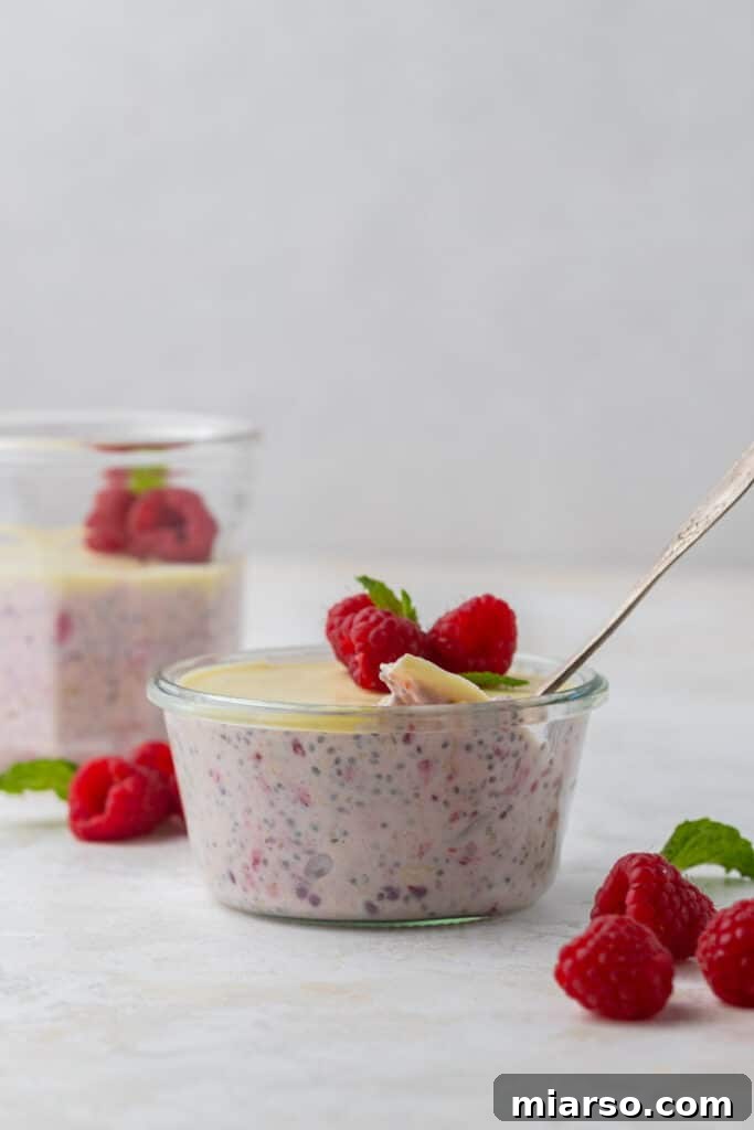 Pink raspberry overnight oats in a cup topped with white chocolate.