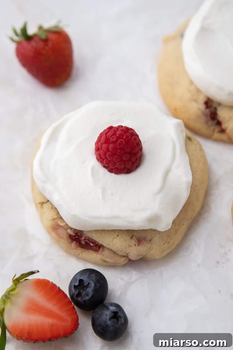 A finished berry cookie with whipped cream and a raspberry topping