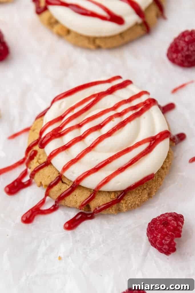 Close-up of a beautifully frosted Crumbl Raspberry Cheesecake Cookie with a vibrant raspberry jam swirl, showcasing its intricate details.