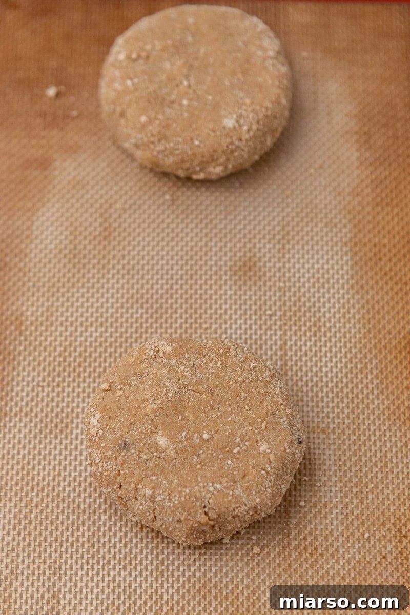 Flattened cookie dough portions on a parchment-lined baking sheet, spaced for even baking.