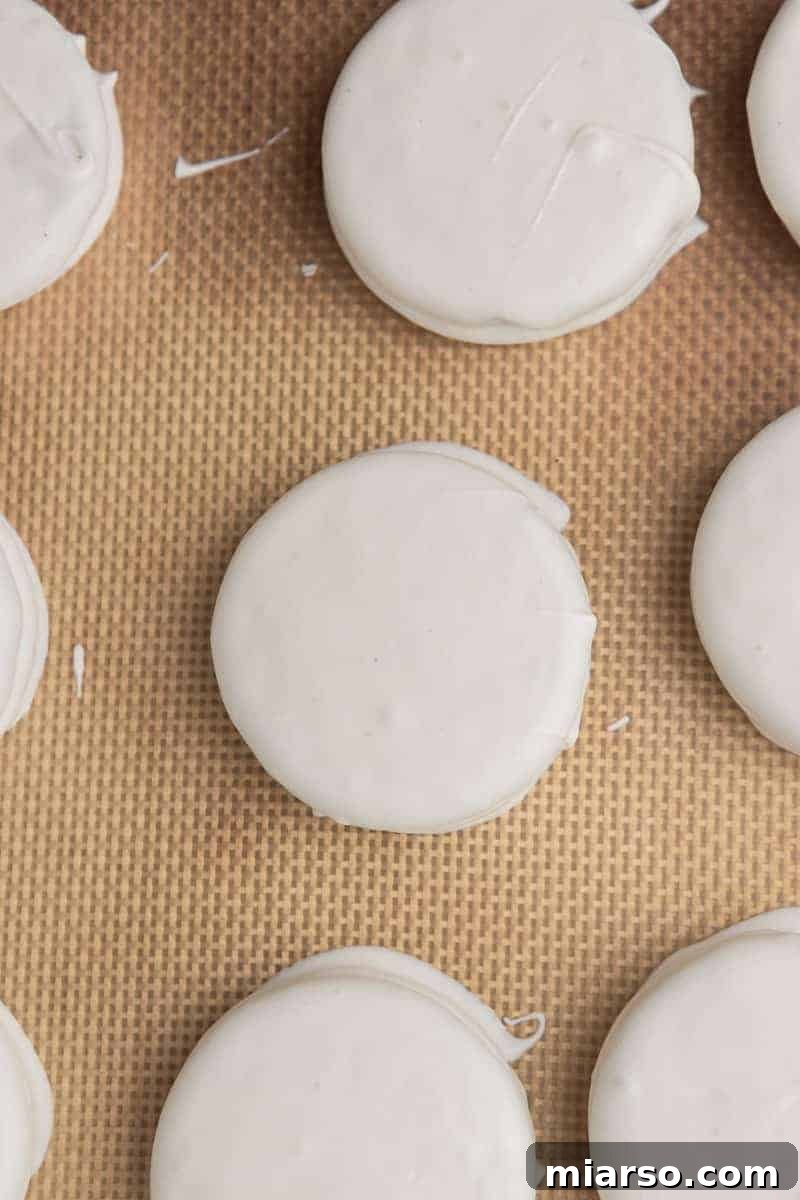Red, White, & Blue Oreo Delights 6 Freshly white chocolate-covered Oreos drying on parchment paper, ready for decoration.