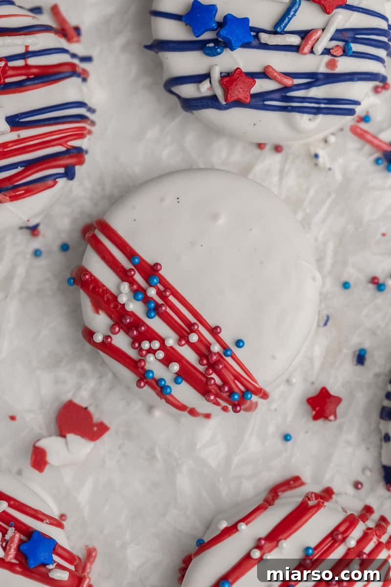 Red, White, & Blue Oreo Delights 7 Close-up of a patriotic Oreo recipe in progress, with red and blue drizzles applied to white chocolate-covered Oreos.