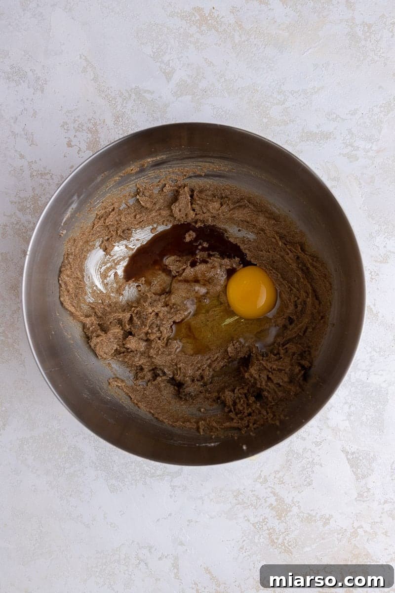 Crumbl Cookie Butter Cookie Crunch Ice Cream 5 Creamed butter and egg in a mixing bowl, illustrating the initial steps of cookie preparation