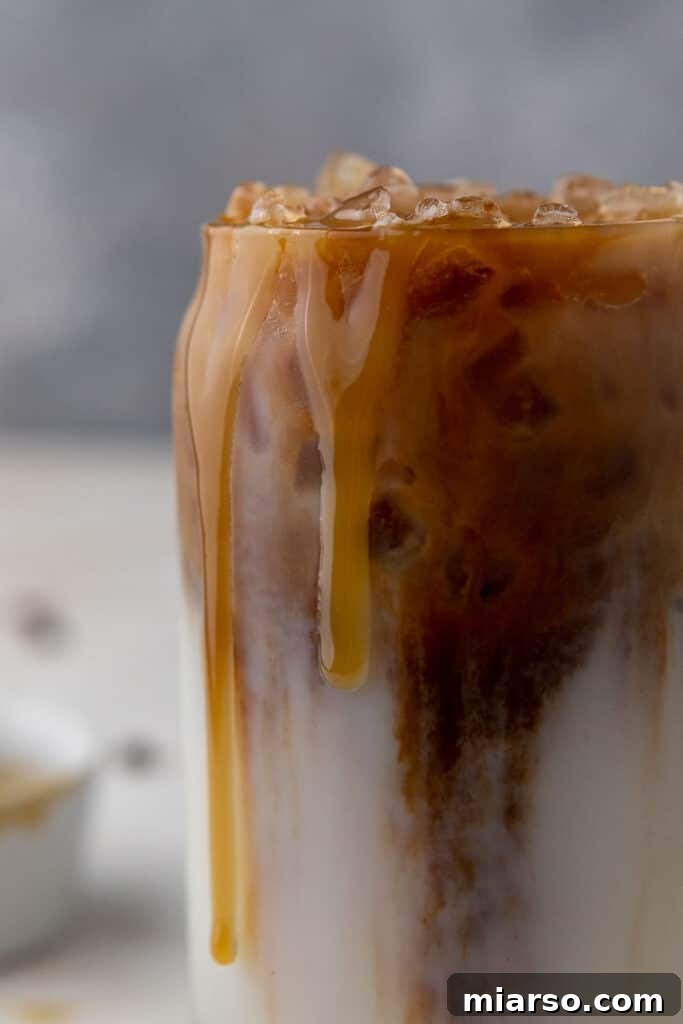 Starbucks Inspired Homemade Iced Caramel Macchiato 2 Close-up of a perfectly layered homemade Starbucks caramel macchiato, showing the rich colors of milk, coffee, and caramel drizzle.