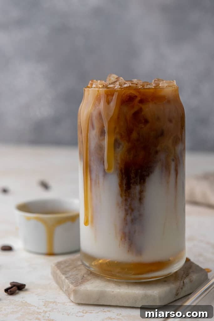 Starbucks Inspired Homemade Iced Caramel Macchiato 8 Clearly visible layers of milk, espresso, and caramel sauce in a transparent glass iced macchiato.