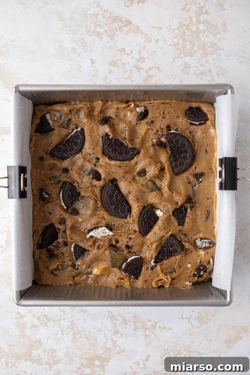 Decadent Oreo Blondie Delights 7 Unbaked Oreo blondies batter spread in a pan with extra Oreos on top