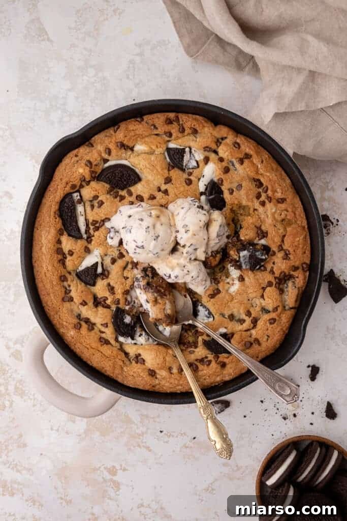 Effortless Giant Oreo Skillet Cookie 10 A large cookies and cream skillet cookie served with multiple scoops of vanilla ice cream, ready to be enjoyed.