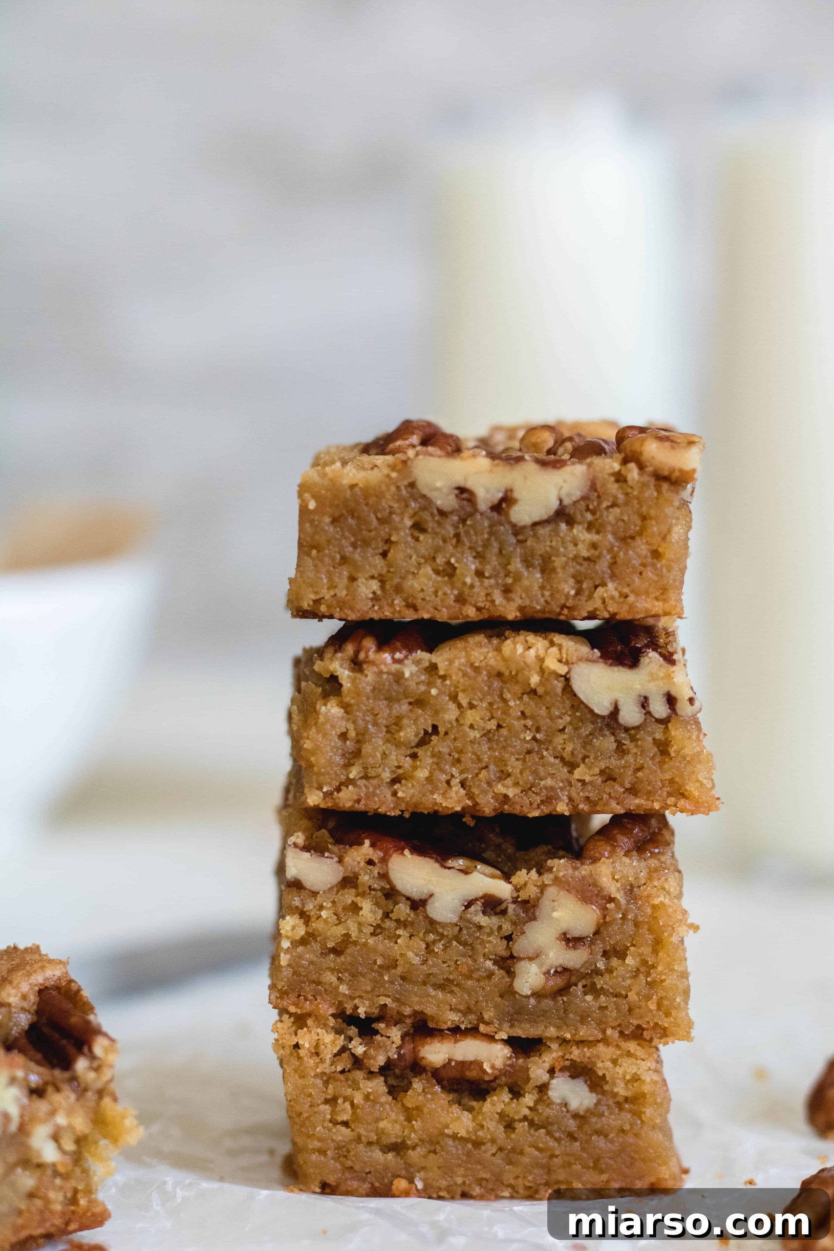 Stacked brown butter pecan blondies glistening with candied pecans, ready to be enjoyed.