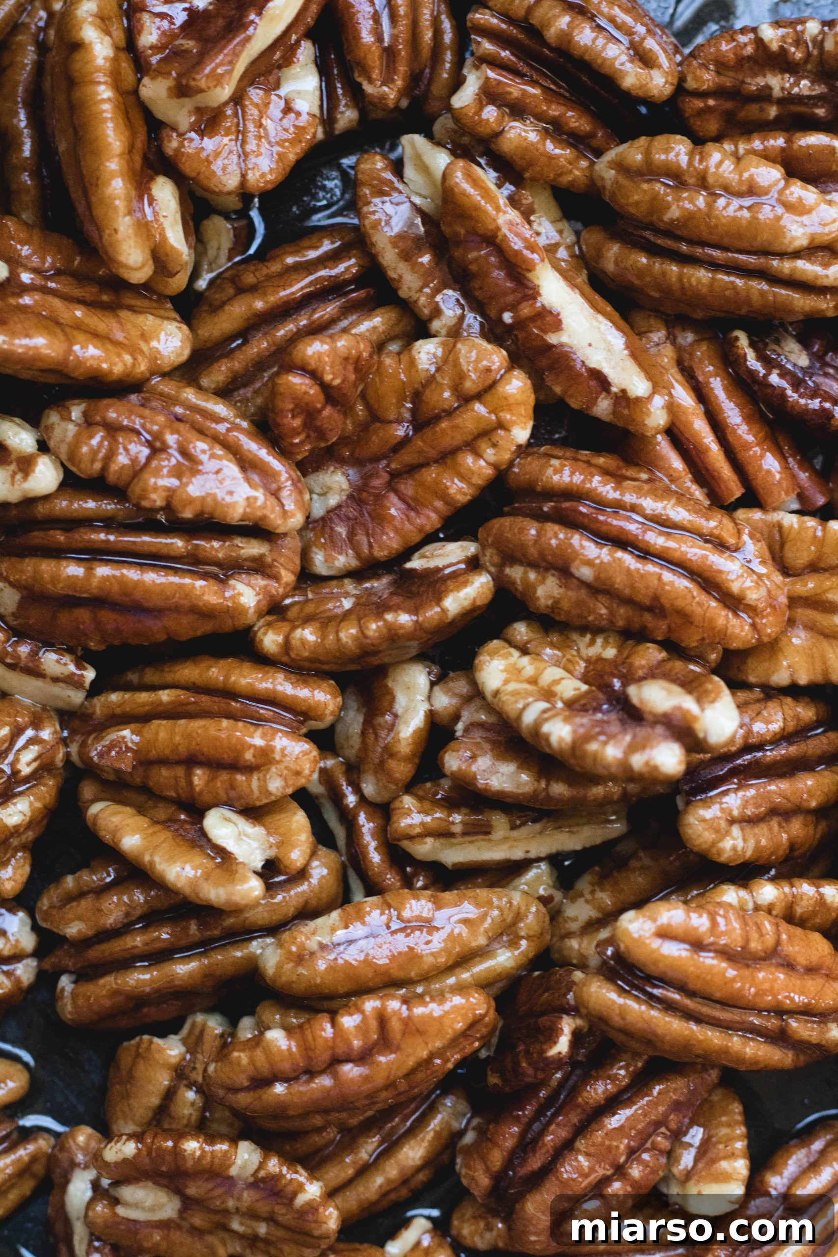 Pecan nuts being coated in maple syrup and butter, turning golden.