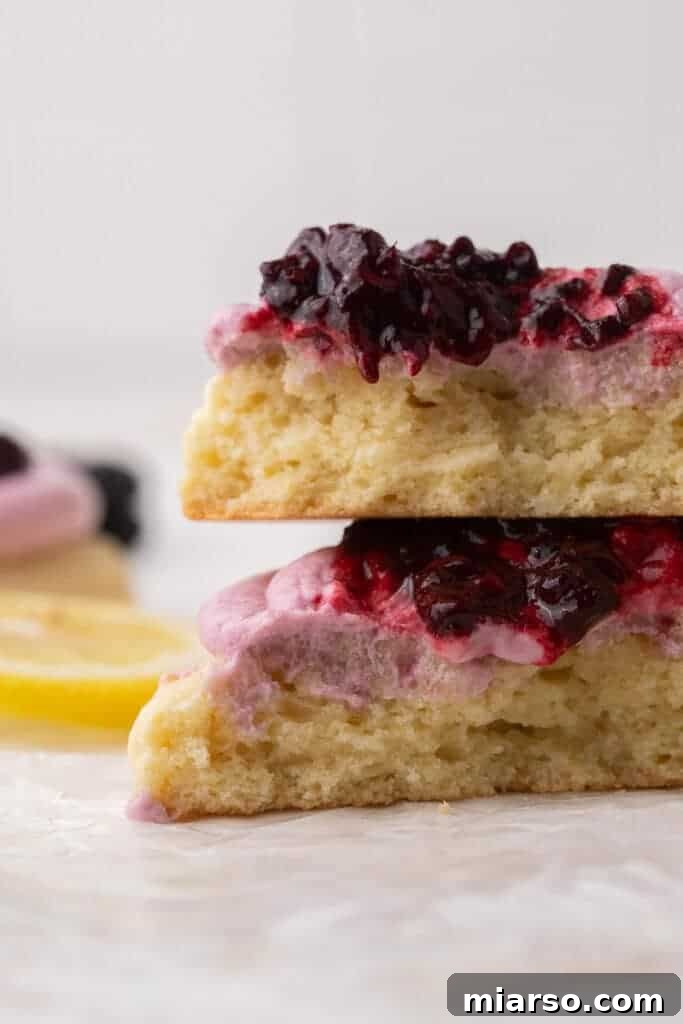 Close up of a lemon blackberry cookie cut in half to show the soft interior and creamy frosting
