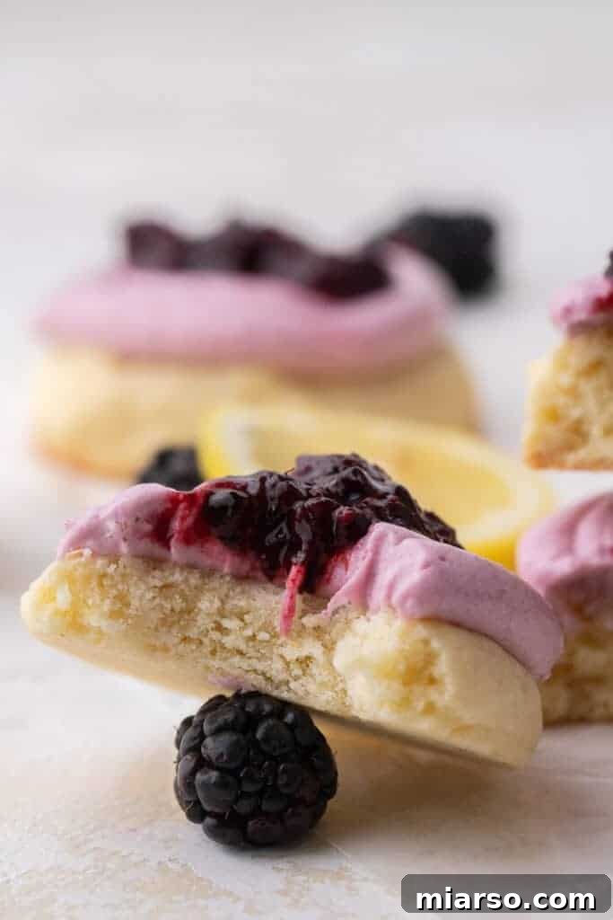 A freshly baked Crumbl lemon blackberry cookie with a bite taken out of it, showing the vibrant frosting and jam