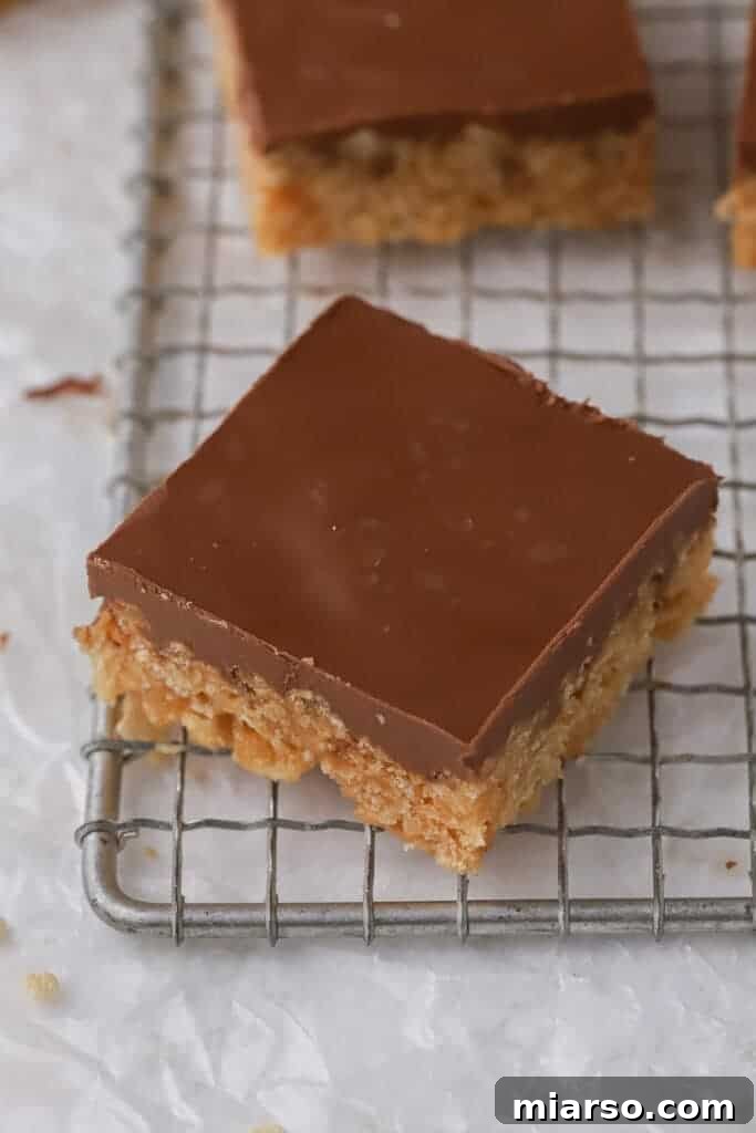 Close-up shot of a perfectly cut Scotcharoos bar, showcasing the crispy rice cereal base and thick chocolate-butterscotch topping.