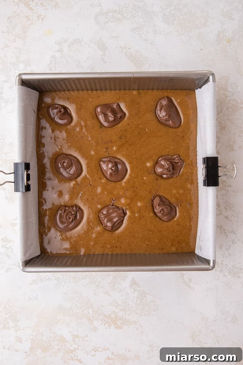 Decadent Nutella Swirl Blondies 7 Blondie batter topped with generous dollops of Nutella, ready for swirling