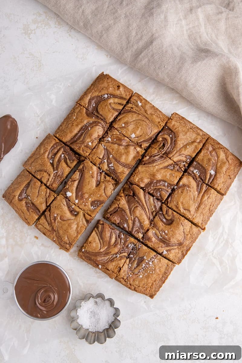 Decadent Nutella Swirl Blondies 9 Freshly baked Nutella blondies resting on parchment paper, cooling down