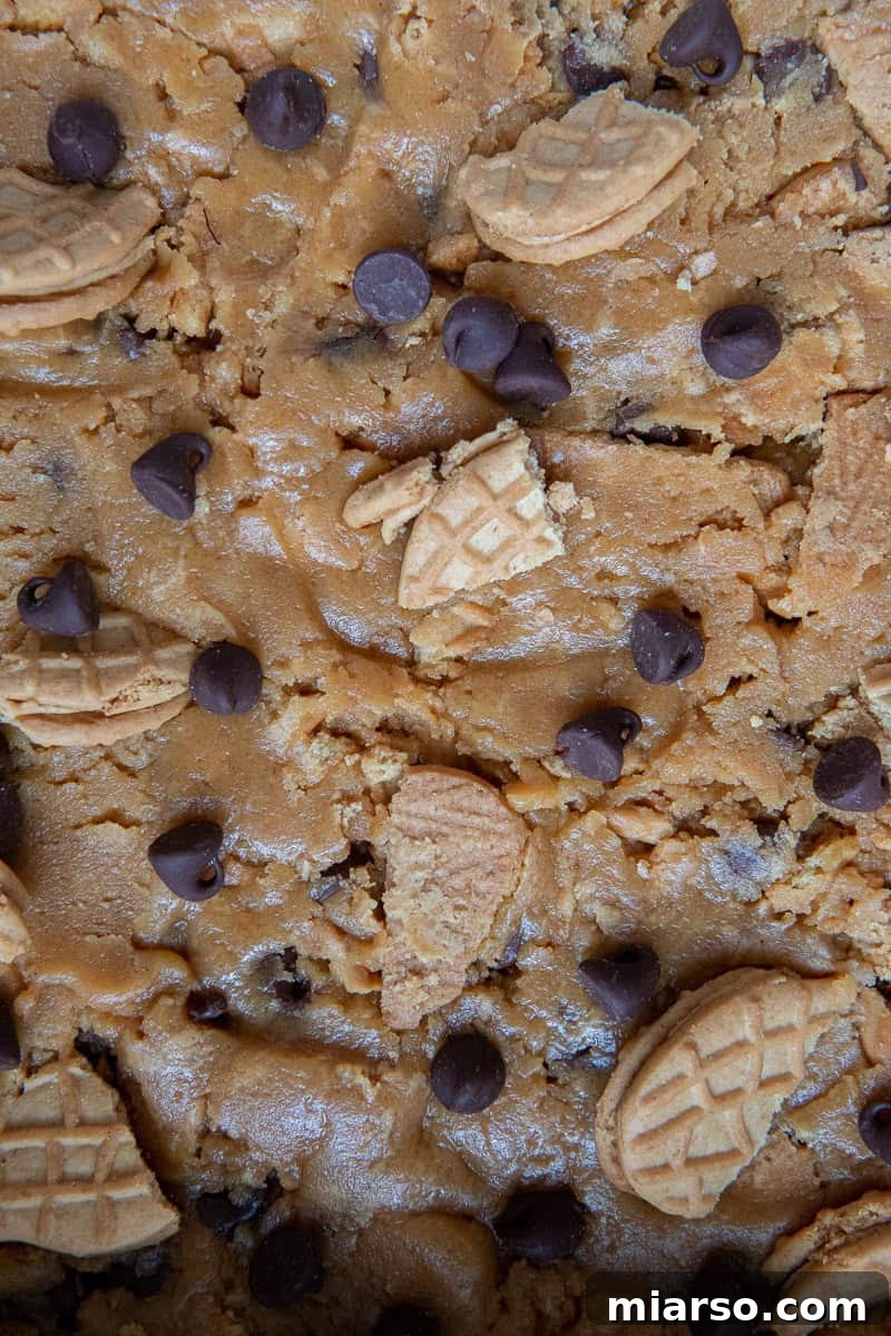 Cookie dough spread evenly in a parchment-lined baking pan.