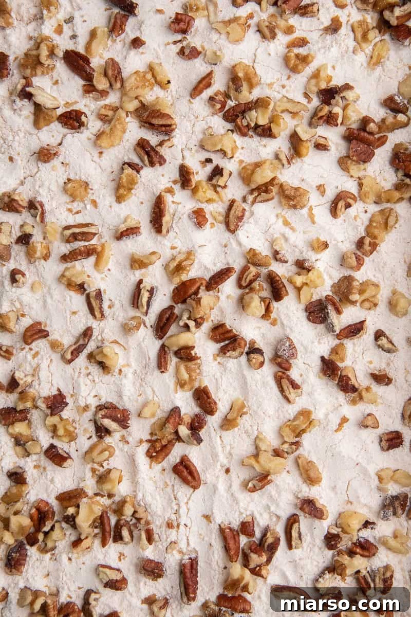Close-up of cake mix and pecan layer sprinkled over pumpkin batter