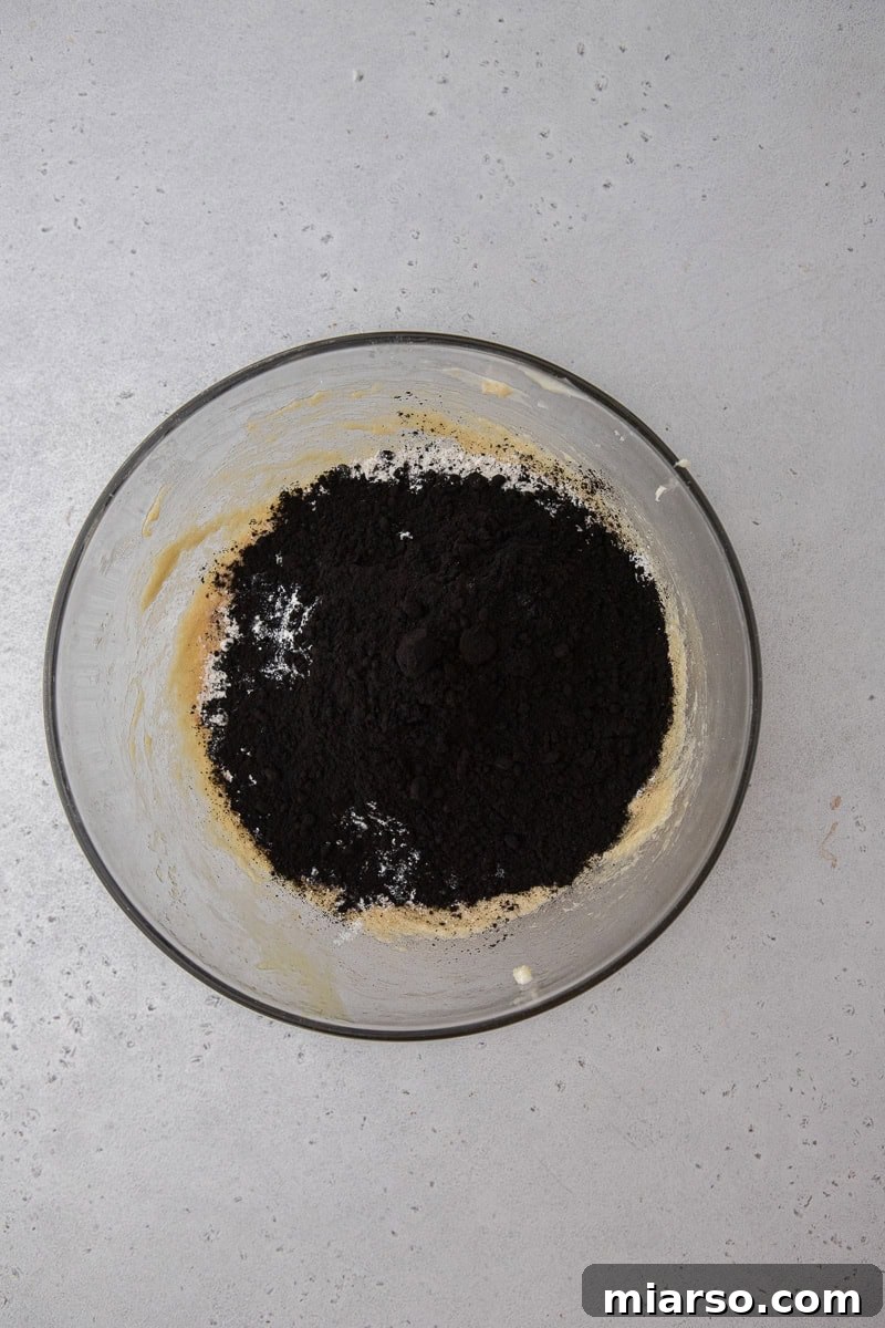 Dry ingredients (flour, black cocoa, baking soda, salt) being added to wet ingredients in a bowl.