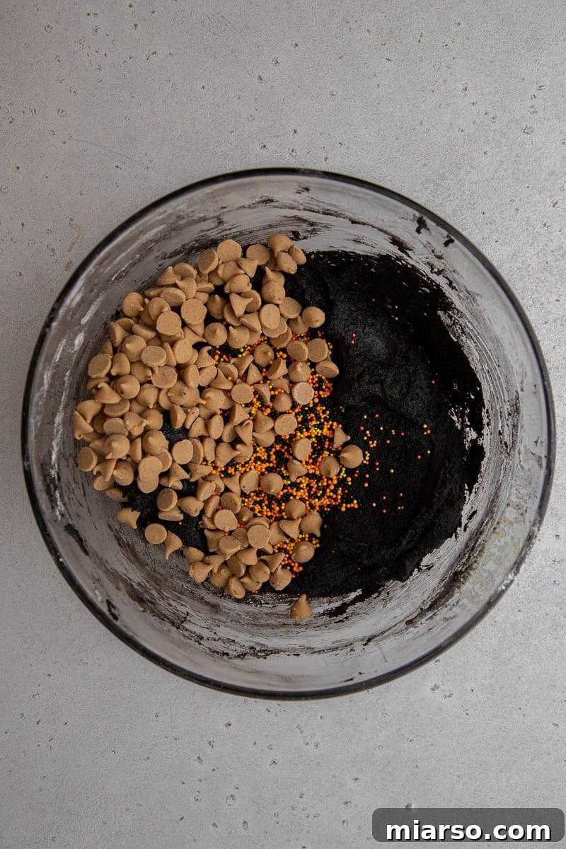 Mixing wet and dry ingredients together in a bowl to form the cookie dough.