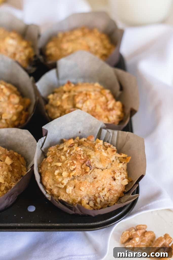 Bakery-Style Banana Walnut Muffins 6 A perfectly baked easy banana walnut muffin on a wooden surface, ready to be enjoyed