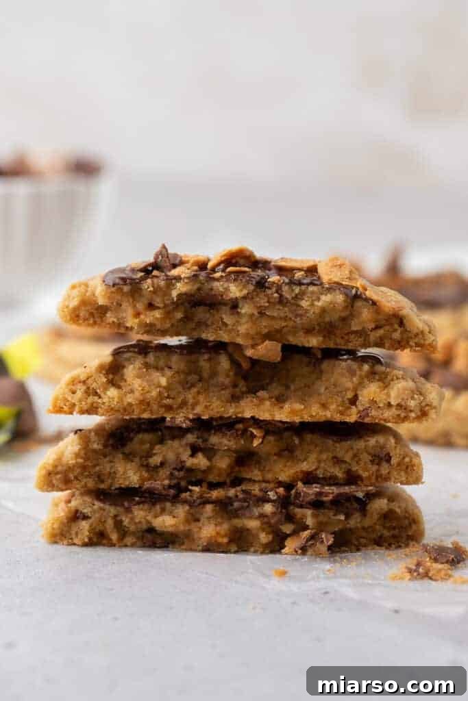 Ultimate Soft and Chewy Butterfinger Cookies 11 Crumbl Butterfinger peanut butter cookies stacked to show soft chewy center with melted chocolate and crunchy Butterfinger pieces