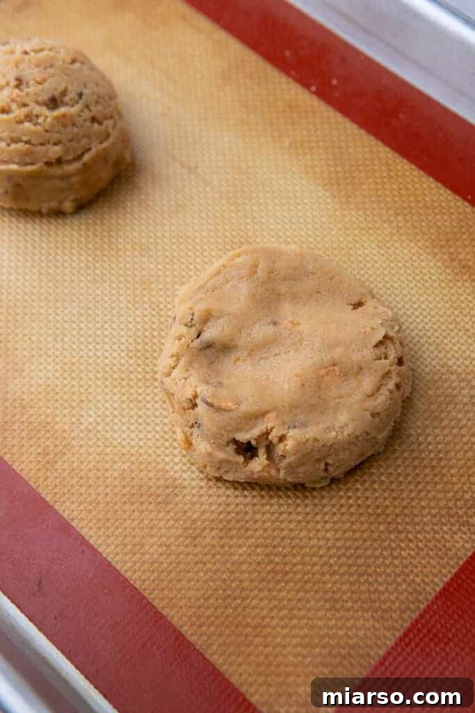Ultimate Soft and Chewy Butterfinger Cookies 8 Flattened cookie dough ready to bake on lined baking sheet