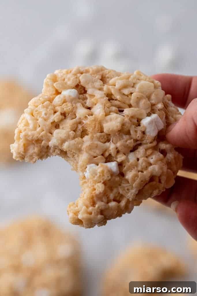 Close-up of a Crumbl rice krispies bar cookie with a bite taken out of it, showcasing its chewy texture and marshmallow bits.