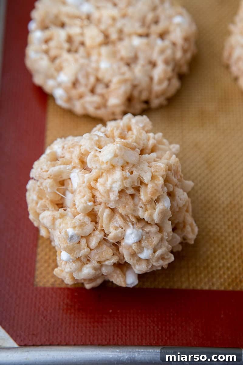 Freshly scooped and shaped no-bake rice krispies bar cookies resting on parchment paper.