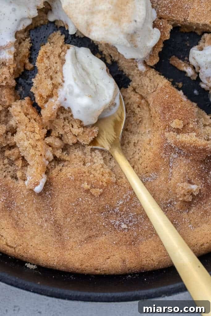 A perfectly baked Snickerdoodle pizookie, golden brown and sprinkled with cinnamon sugar, served hot in its cast iron skillet.