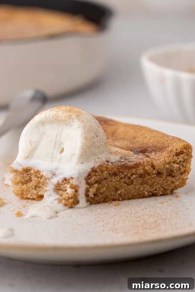 A warm Snickerdoodle pizookie in a cast iron skillet, garnished with a sprinkle of cinnamon, ready for a cozy dessert experience.