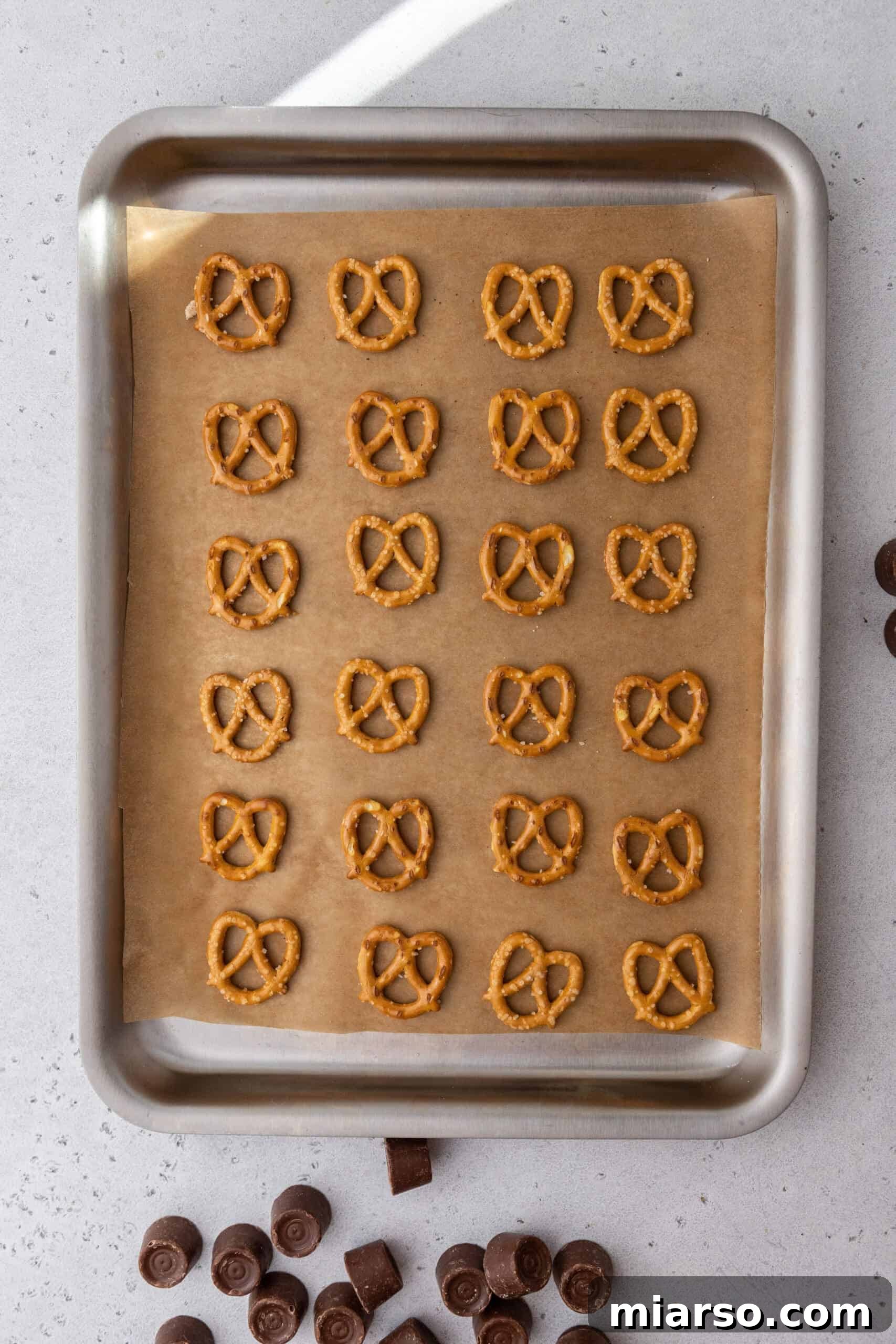 Pretzels arranged on a parchment-lined baking sheet, ready for Rolos.