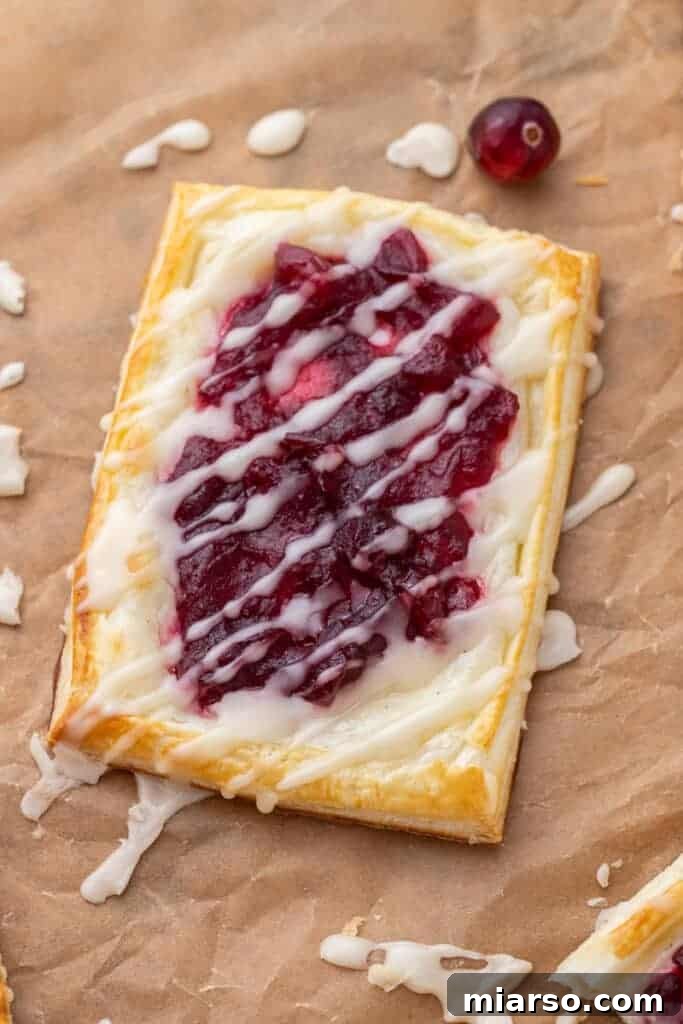 Cranberry Cheese Danish Revival 2 Cranberry sauce cheese danish, a flaky pastry with cream cheese and bright red cranberry sauce, drizzled with glaze, ready to be enjoyed as a holiday breakfast or brunch.