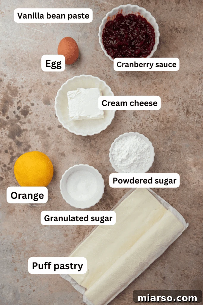 Cranberry Cheese Danish Revival 3 Various ingredients for cranberry cheese danish spread on a clean white countertop, including cream cheese, sugar, puff pastry, and cranberry sauce.