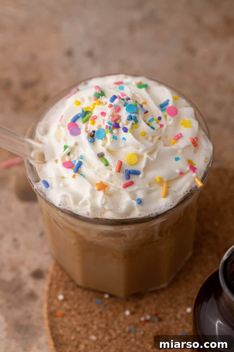 A tall glass of iced latte made with homemade simple syrup, showcasing the creamy, inviting color of the festive drink.