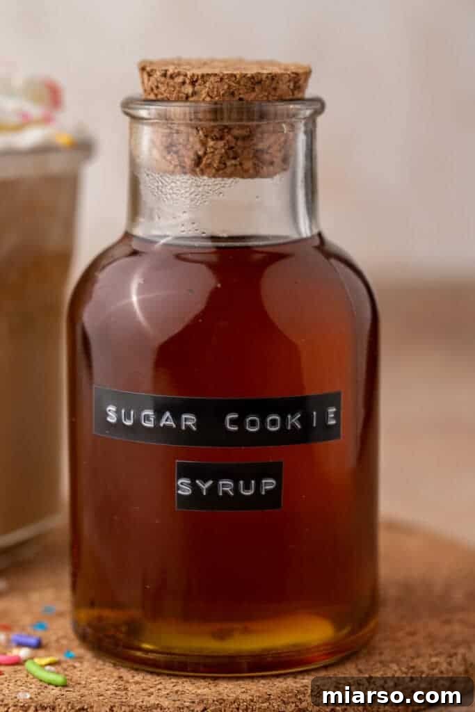 A close-up shot of the homemade Starbucks Sugar Cookie Syrup, highlighting its clear, golden hue and inviting texture in a glass bottle.