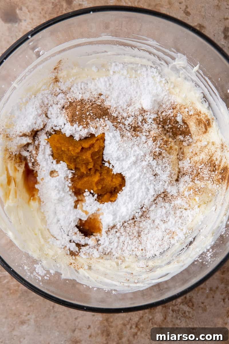 Decadent Crumbl Chocolate Pumpkin Cheesecake Cookies 10 Creamy pumpkin cream cheese frosting being prepared