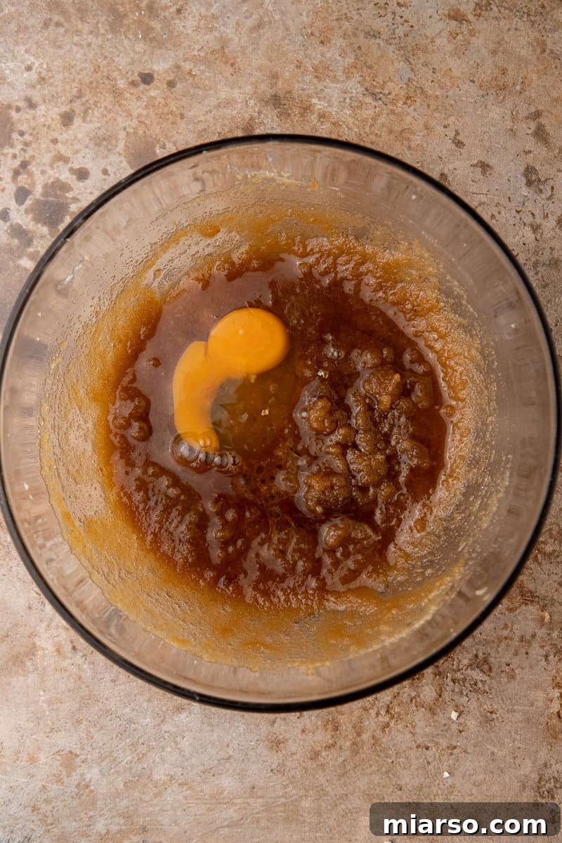 Irresistible Holiday M&M's Blondies 5 Wet ingredients (butter, sugar, egg, vanilla) being mixed in a bowl for blondies