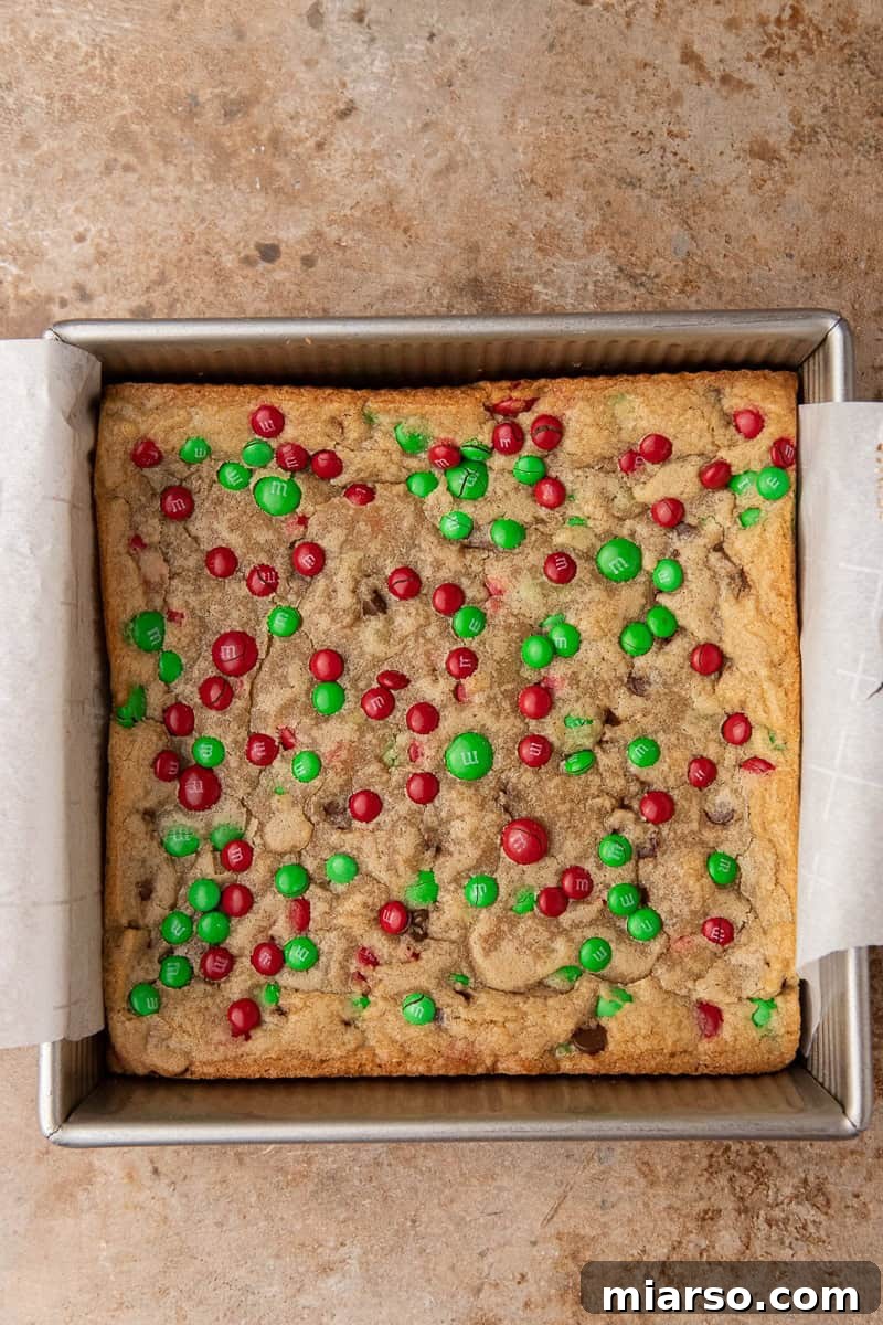 Irresistible Holiday M&M's Blondies 8 Blondie cookie dough spread evenly in a parchment-lined 8x8 baking pan, ready for oven