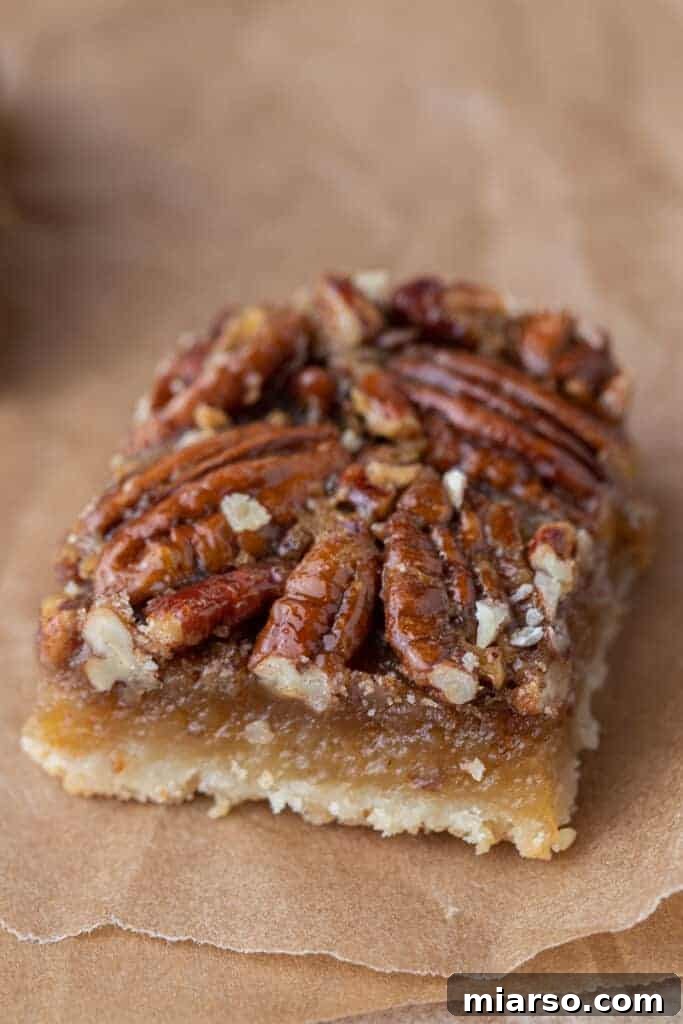 A close-up shot of a single pecan pie bar slice, showing the perfect layers.