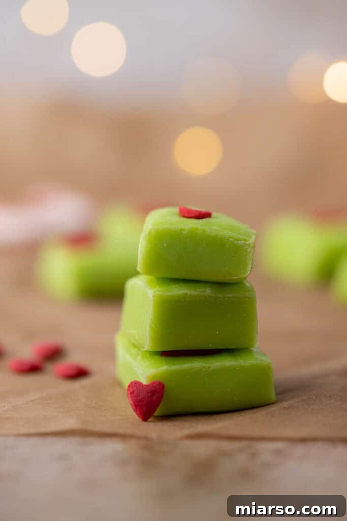 Grinch's Heart-Melting Fudge 2 Stack of thick green grinch fudge, perfectly cut and showing its vibrant color, topped with small red candy hearts.