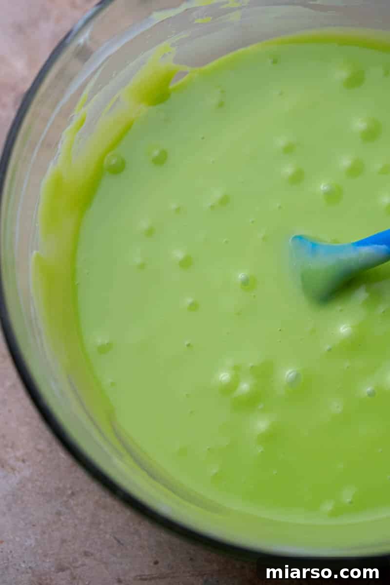 Grinch's Heart-Melting Fudge 5 Close-up of melted white chocolate and sweetened condensed milk, showing its smooth texture before coloring.