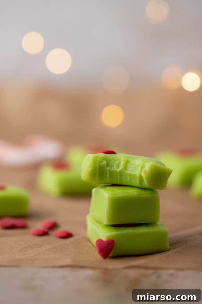 Grinch's Heart-Melting Fudge 9 Stack of thick, perfectly cut green Grinch fudge squares with red heart sprinkles, ready for a holiday treat.
