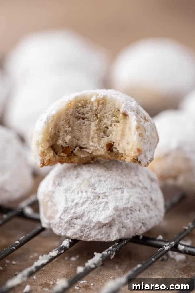 Melt-in-Your-Mouth Snowball Perfection 2 Stacked snowball cookies dusted with powdered sugar, ready to be served during the holidays.