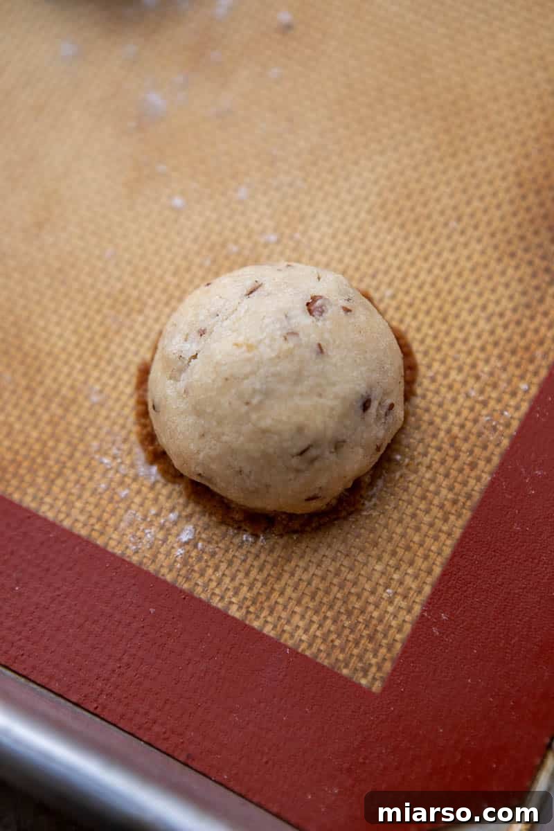 Melt-in-Your-Mouth Snowball Perfection 9 Freshly baked warm cookies on a baking sheet, with slightly golden edges, just out of the oven.