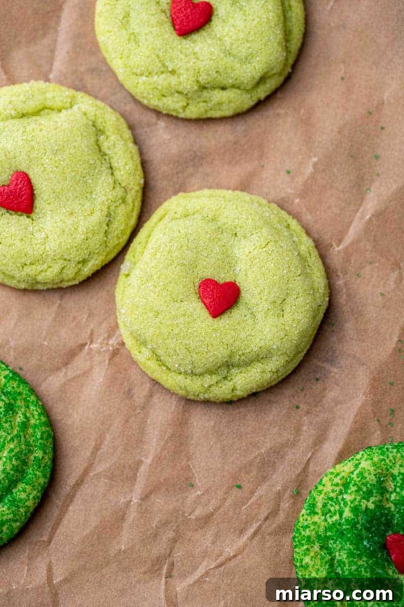 Grinch's Heart-Melting Sugar Cookies 12 Grinch cookies rolled in granulated sugar on a baking sheet, showing a classic finish