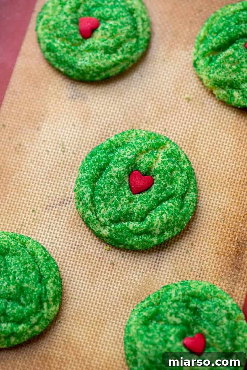 Grinch's Heart-Melting Sugar Cookies 13 Grinch cookies rolled in green sprinkles on a baking sheet, for a more festive look