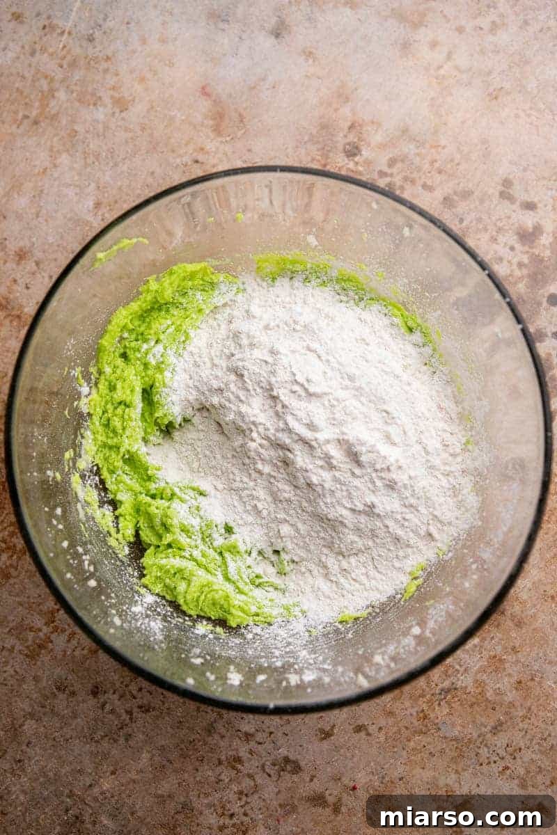 Grinch's Heart-Melting Sugar Cookies 7 Vibrant green cookie dough in a mixing bowl, ready for shaping