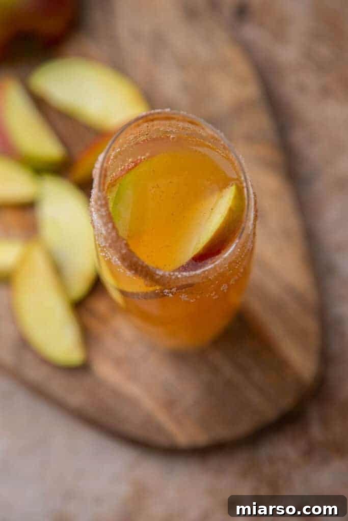 Sparkling 5-Minute Apple Cider Mimosas 4 Overhead shot of two apple cider mimosas, garnished with apple slices, on a wooden table.
