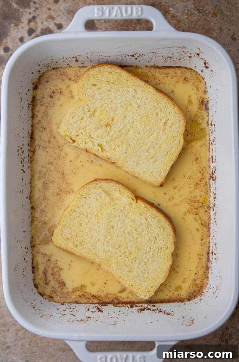 The Ultimate Brioche French Toast 5 A slice of brioche bread soaking thoroughly in the creamy egg custard mixture, ensuring even coating