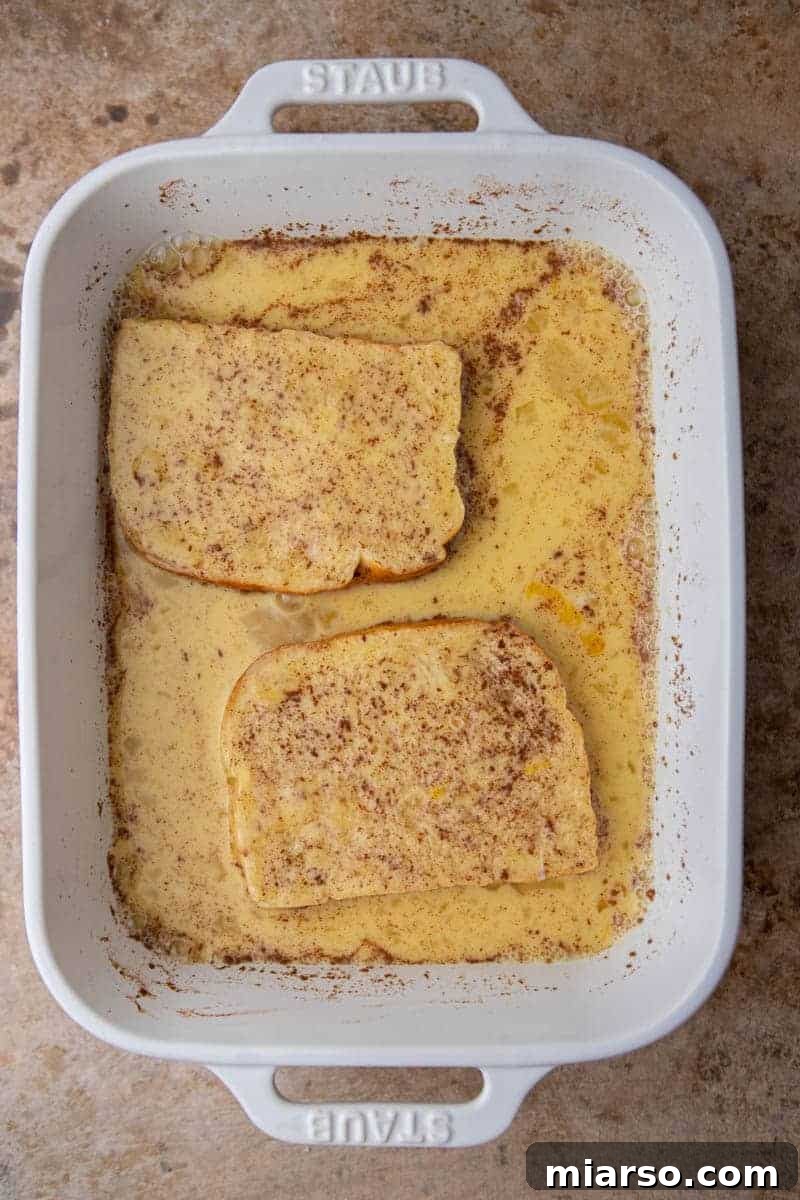 The Ultimate Brioche French Toast 6 Another perspective of brioche bread absorbing the rich custard, highlighting the preparation step