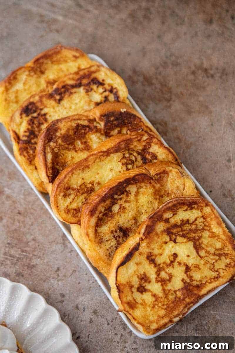 The Ultimate Brioche French Toast 7 Two slices of brioche French toast sizzling in a hot skillet, achieving a perfect golden-brown color